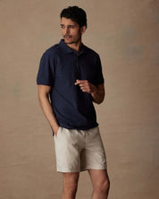 Model wearing a Short Sleeve Honeycomb Pique Polo Shirt in Peacoat with shorts, showcasing a classic and comfortable style.