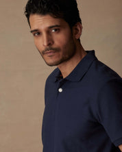 Model wearing a short sleeve honeycomb pique polo shirt in peacoat, showcasing a classic fit and ribbed collar.