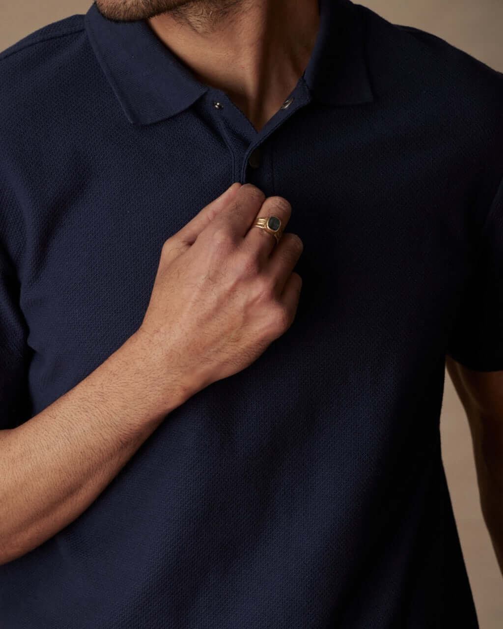 Close-up of a man in a short sleeve honeycomb pique polo shirt in peacoat with ribbed collar and snap placket.