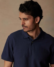 Man in a short sleeve honeycomb pique polo shirt, peacoat color, showcasing classic style and ribbed collar.