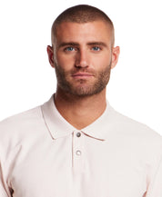 Model wearing a short sleeve pink honeycomb pique polo shirt with ribbed collar and snap placket.