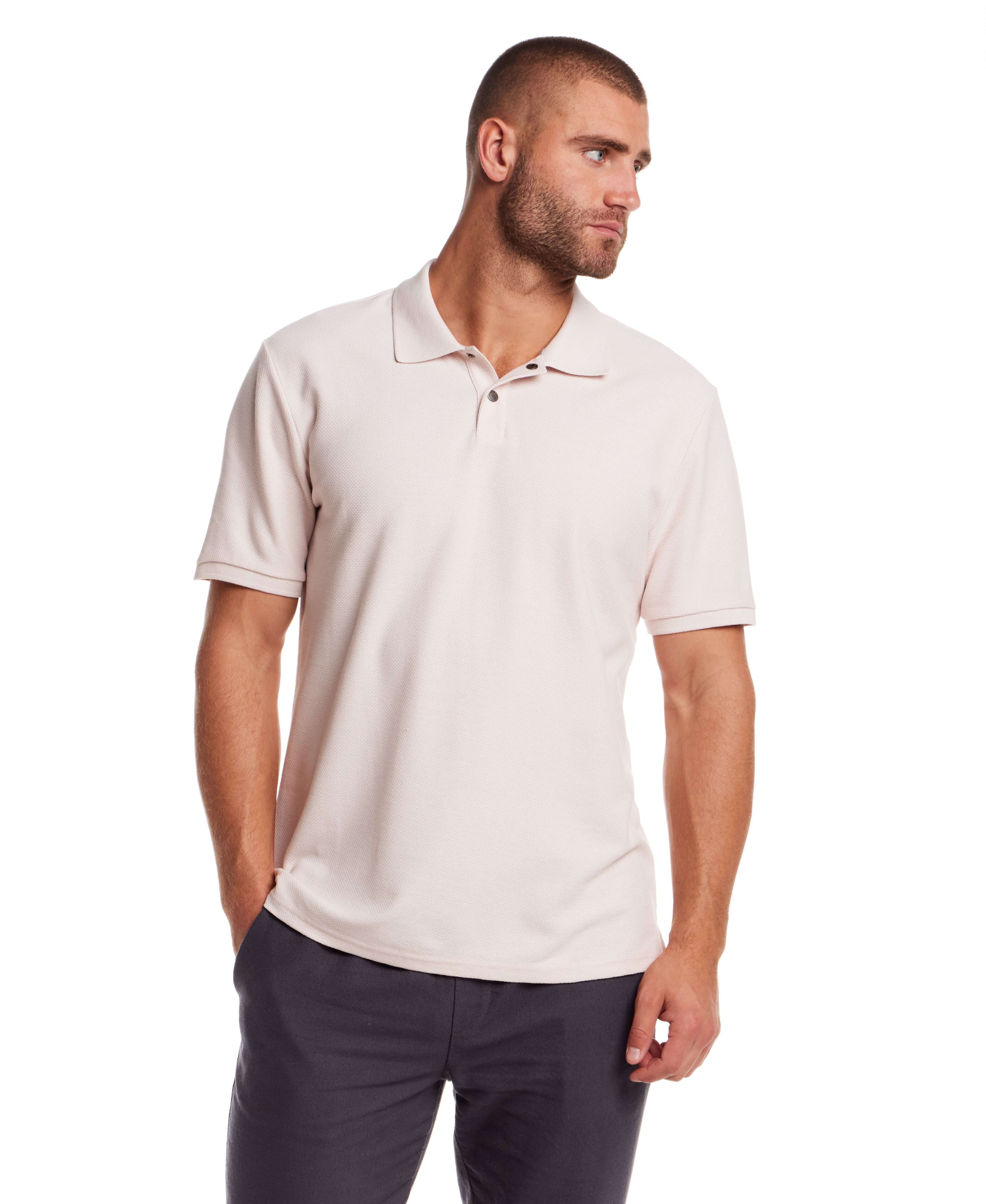 Man in short sleeve pink honeycomb pique polo shirt with ribbed collar and cuffs, modeling classic fit.