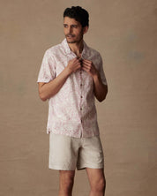 Model wearing a short sleeve linen cotton camp shirt in wild rose with a camp collar and button closure.