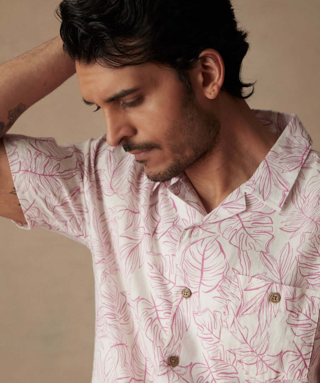 Man wearing a short sleeve linen cotton camp shirt in Wild Rose with leaf print, showcasing a relaxed casual style.