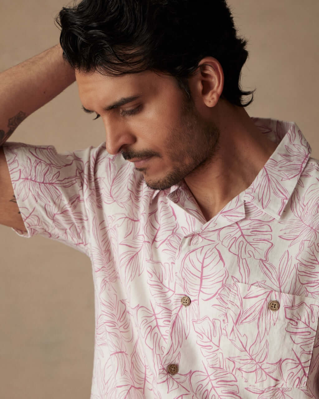 Man wearing a short sleeve linen cotton camp shirt in Wild Rose with leaf print, showcasing a relaxed casual style.