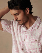 Man wearing a short sleeve linen cotton camp shirt in Wild Rose with leaf print, showcasing a relaxed casual style.