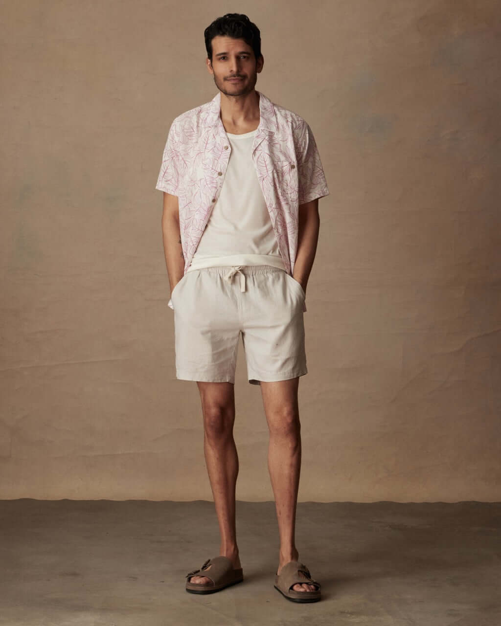 Man wearing a Short Sleeve Linen Cotton Camp Shirt in Wild Rose, paired with beige shorts and sandals.