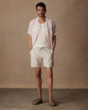 Man wearing a Short Sleeve Linen Cotton Camp Shirt in Wild Rose, paired with beige shorts and sandals.