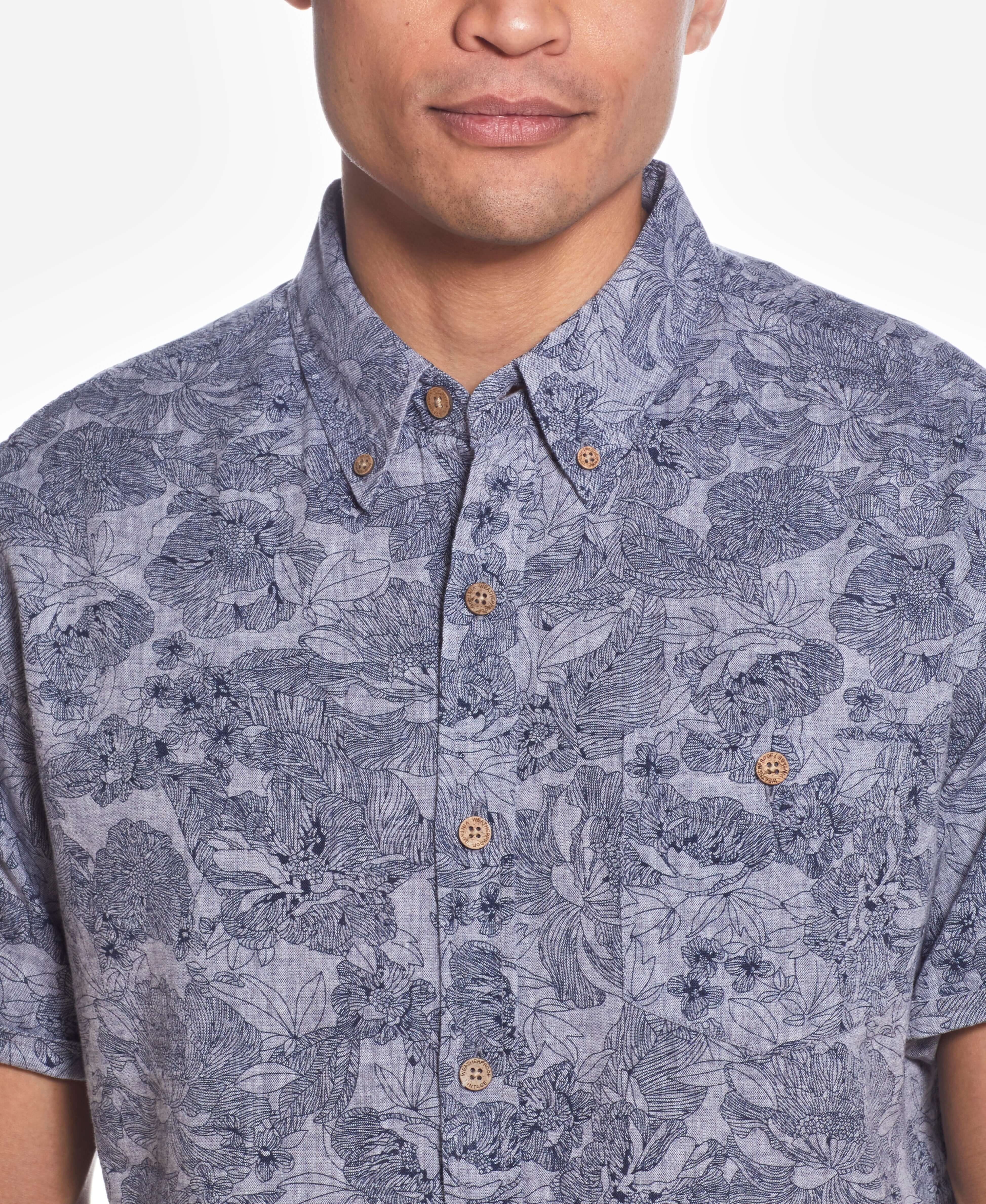 Short Sleeve Linen Cotton Floral Print In Bering Sea worn by a model, featuring a button down collar and cuffed short sleeves.