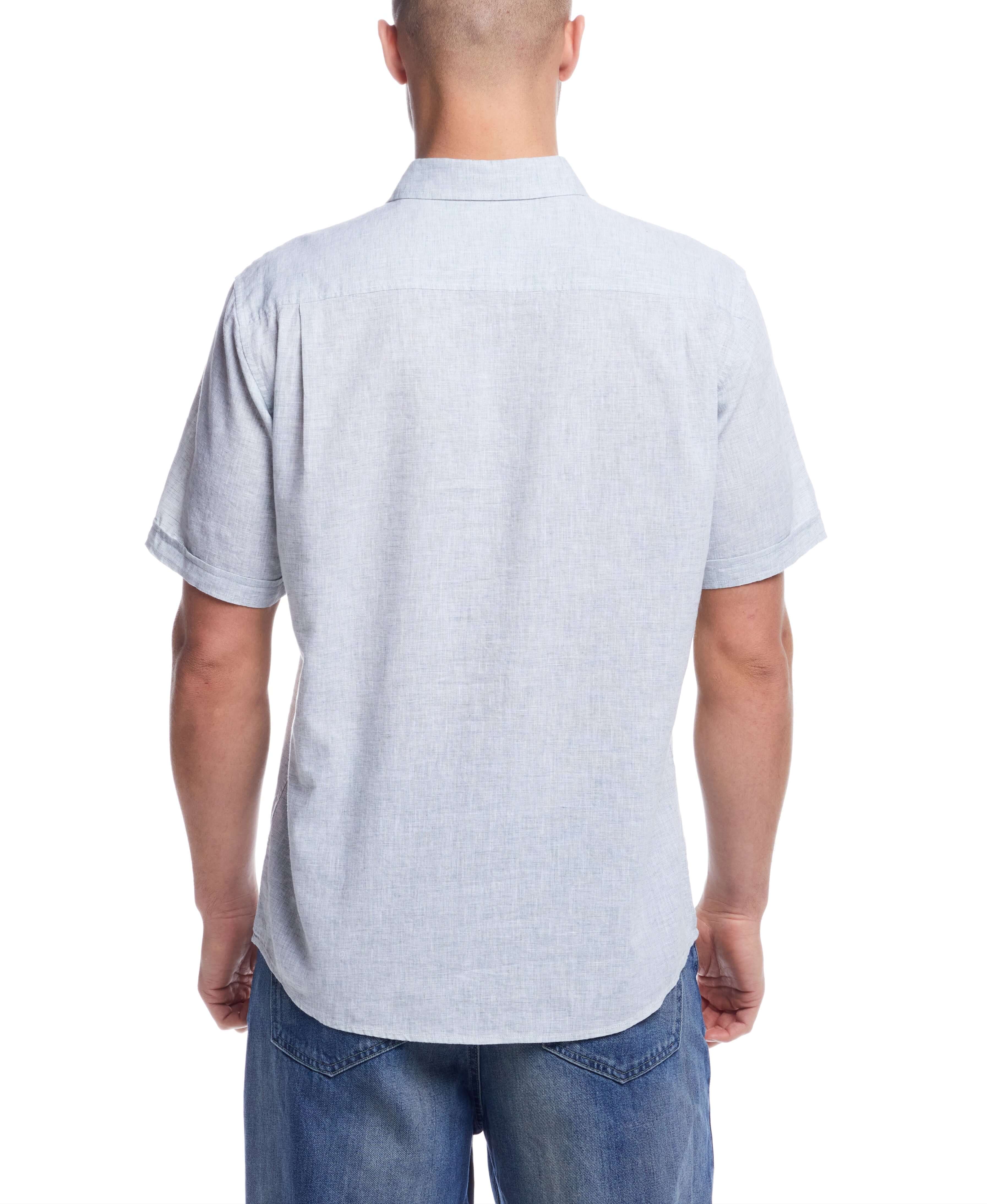 Back view of a man wearing a short sleeve solid linen cotton shirt in a light color, showcasing a modern and relaxed fit.