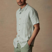 Short sleeve linen shirt in teal mist with button closure, chest pocket, and classic fit, worn by model.