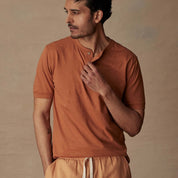 Man wearing a short sleeve melange henley shirt in adobe color, showcasing its classic fit and comfort.