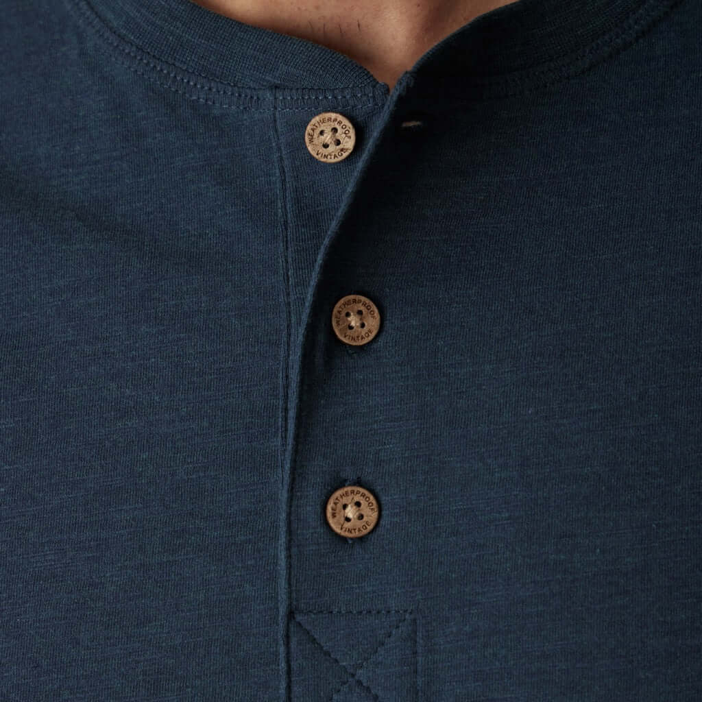 Close-up of deep cobalt henley shirt with button placket and ribbed details, showcasing quality craftsmanship.