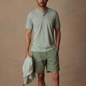 Model wearing a short sleeve melange henley in sea mist heather with green shorts, showcasing comfort and classic style.