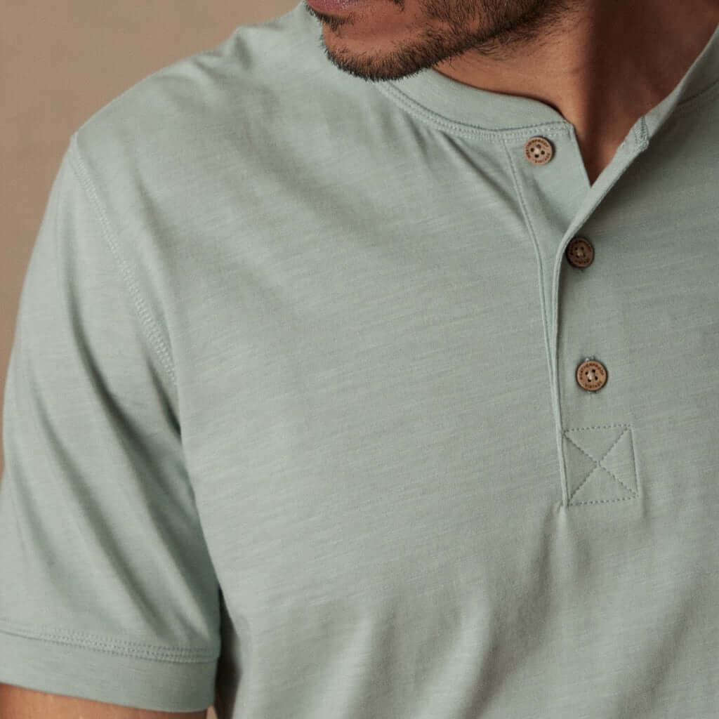 Close-up of a man wearing a short sleeve melange henley in sea mist heather with a 3-button placket.