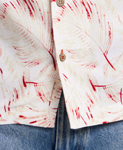 Short sleeve rayon camp shirt in dusty pink with a retro leaf pattern, paired with blue jeans, showcasing front buttons and pocket.