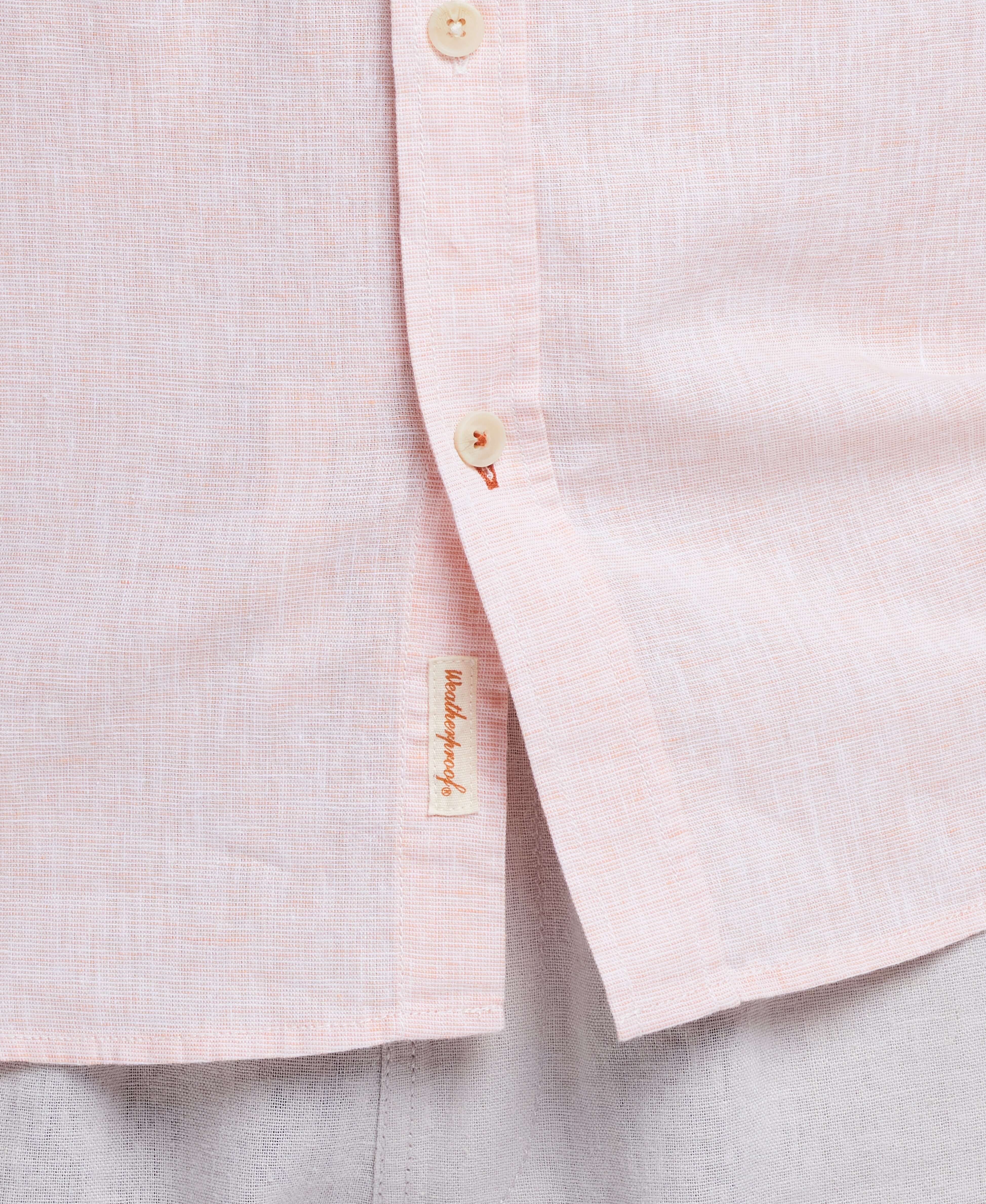 Close-up of a light pink linen shirt with buttons, featuring a casual and stylish blend of comfort and elegance.