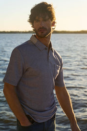 Short sleeve twill polo in Peacoat Navy worn by a man by the water, featuring a classic design and pocket detail.
