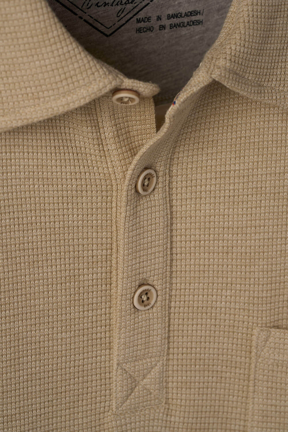 Close-up of Short Sleeve Waffle Polo in Bleached Sand, featuring waffle texture and three-button placket.
