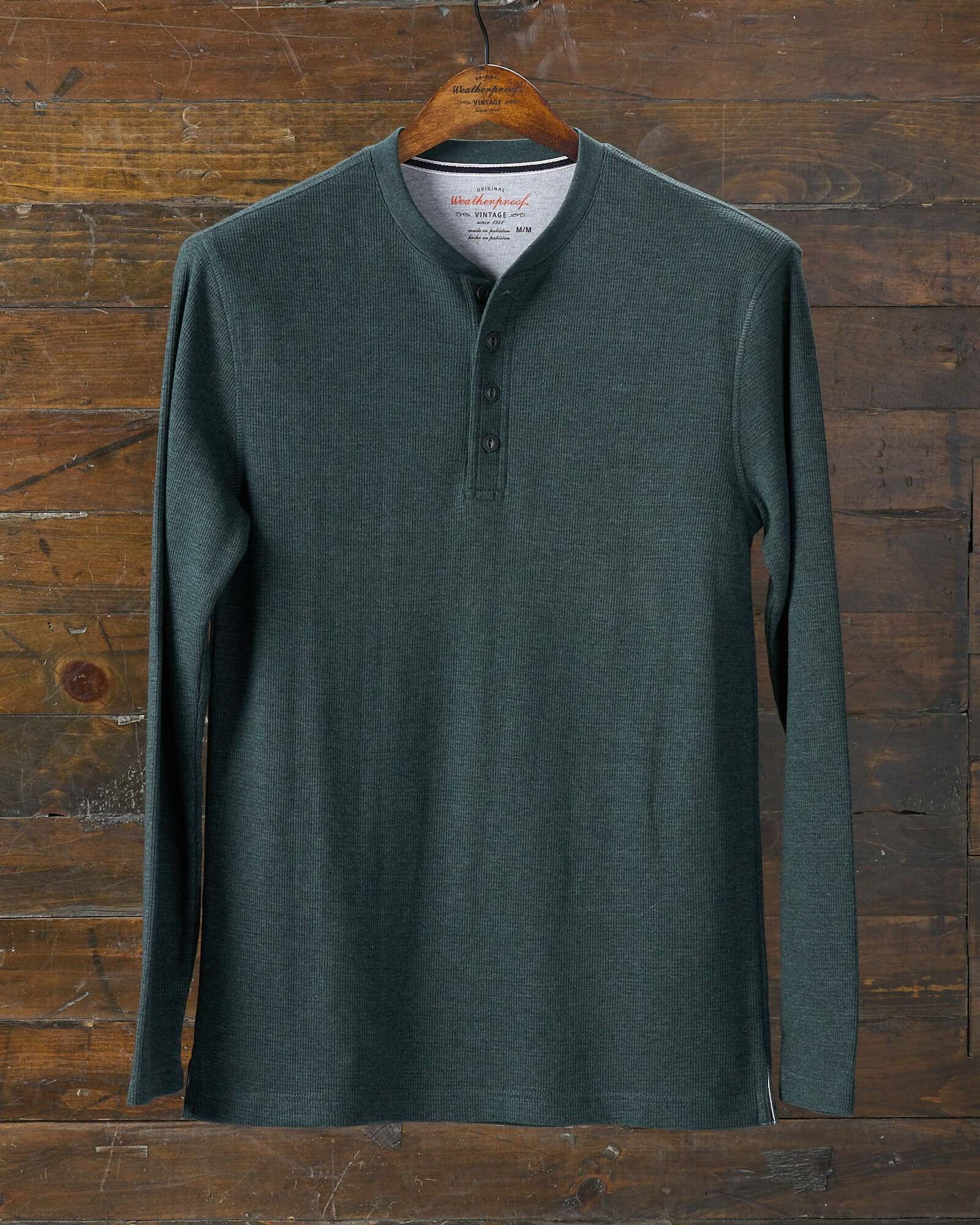 Long Sleeve Waffle Henley in Heather Scarab displayed on a wooden hanger against a rustic background.
