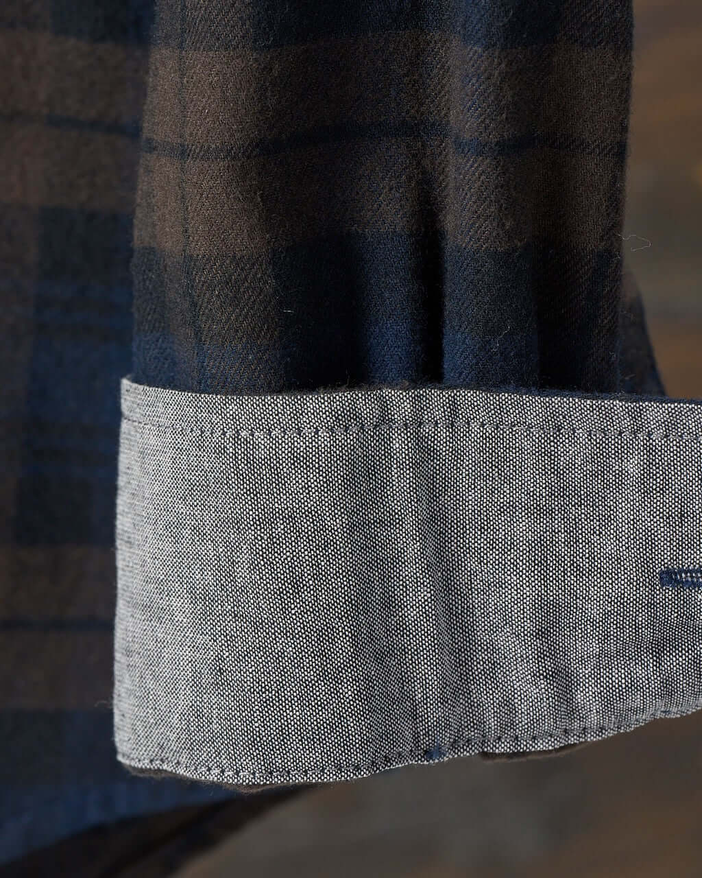 Close-up of the cuff of a long sleeve brushed flannel shirt in toffee and blue, featuring a button-down design.