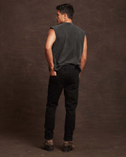 Model showcasing slim fit denim jeans in jet black from the back, paired with a sleeveless top and boots.