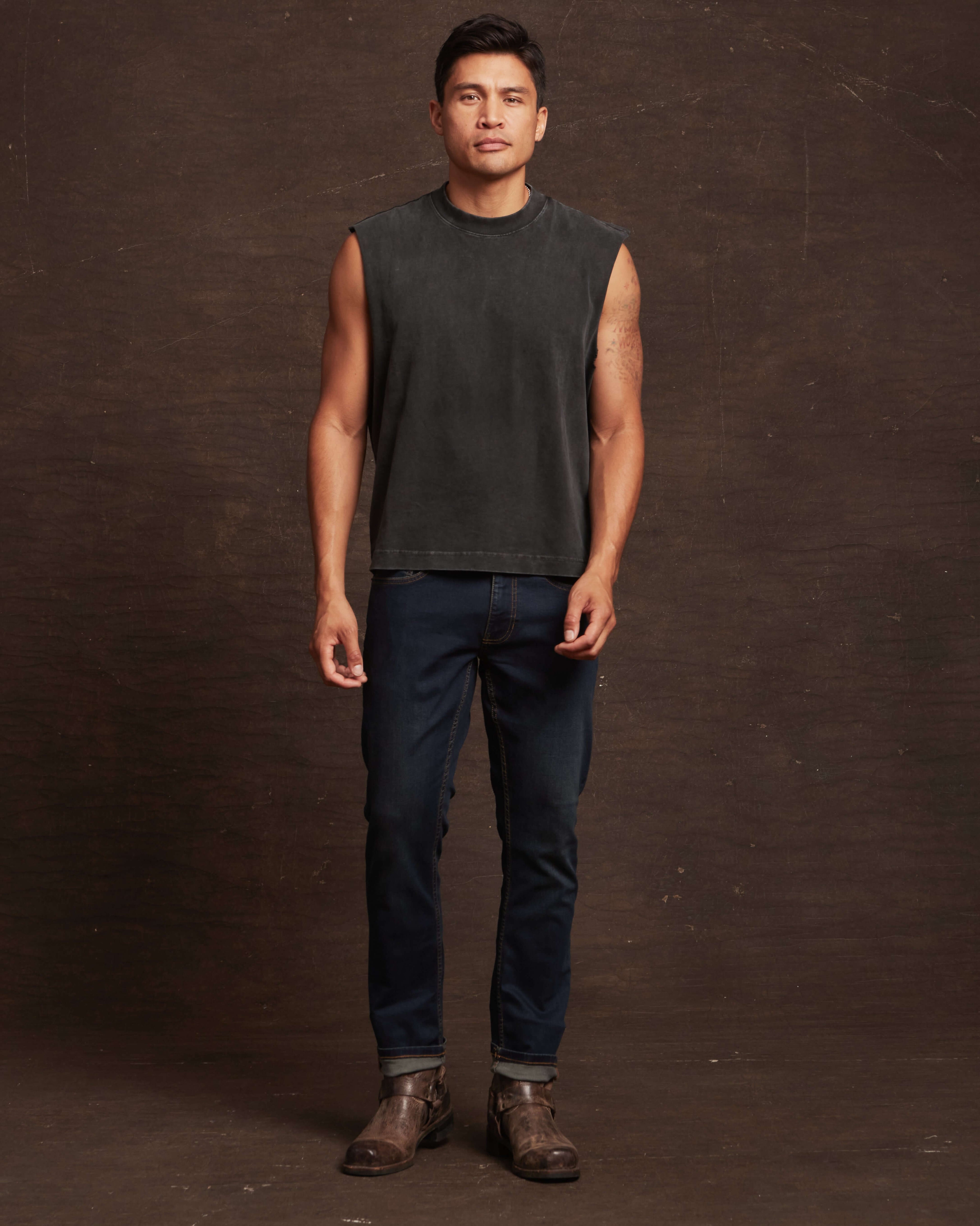 Man in sleeveless top and slim fit moon shadow denim jeans, showcasing a modern and stylish casual look.
