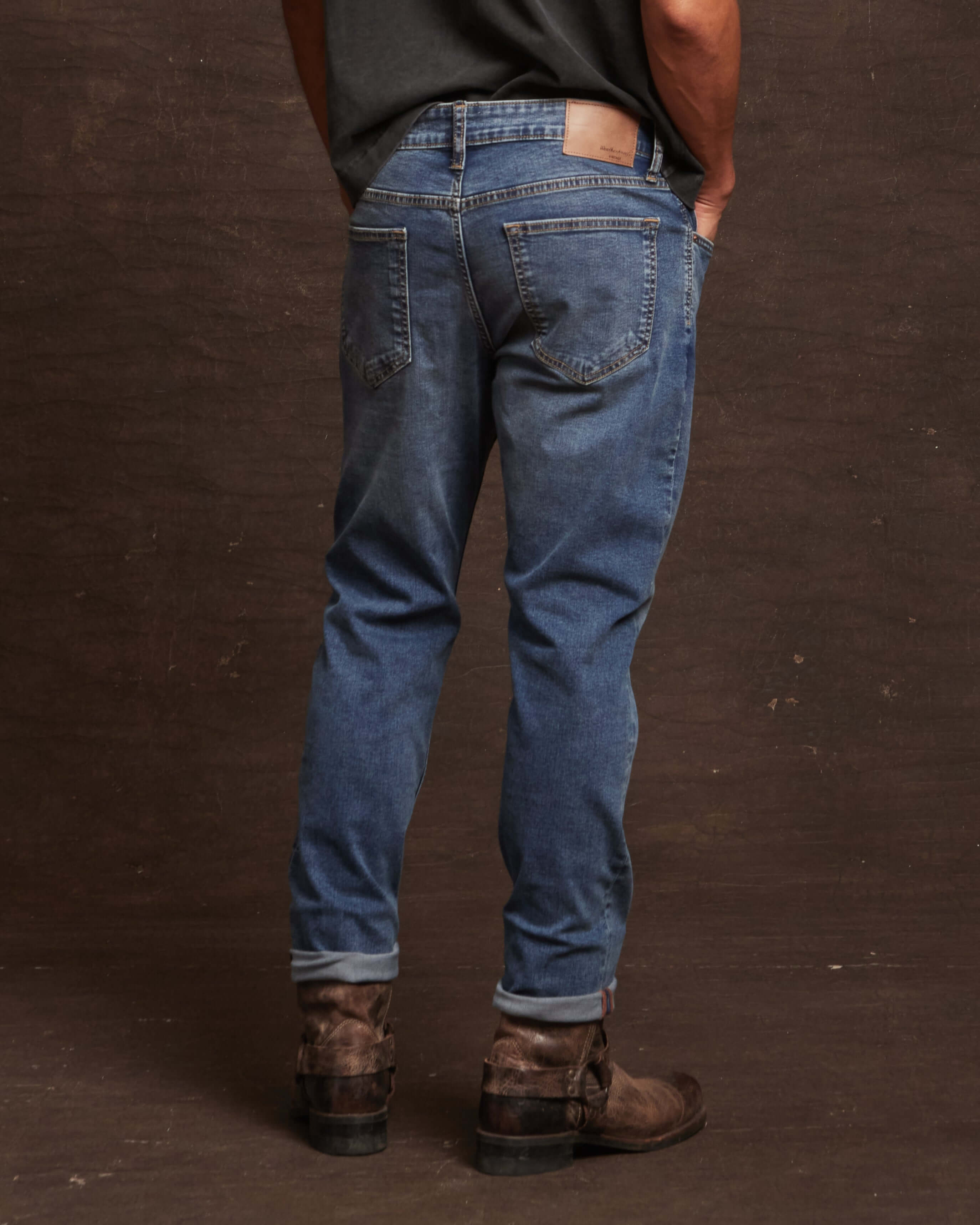 Man showcasing slim fit denim jeans in Rocker Blue, featuring a comfortable all-way stretch and stylish cuffed hem.