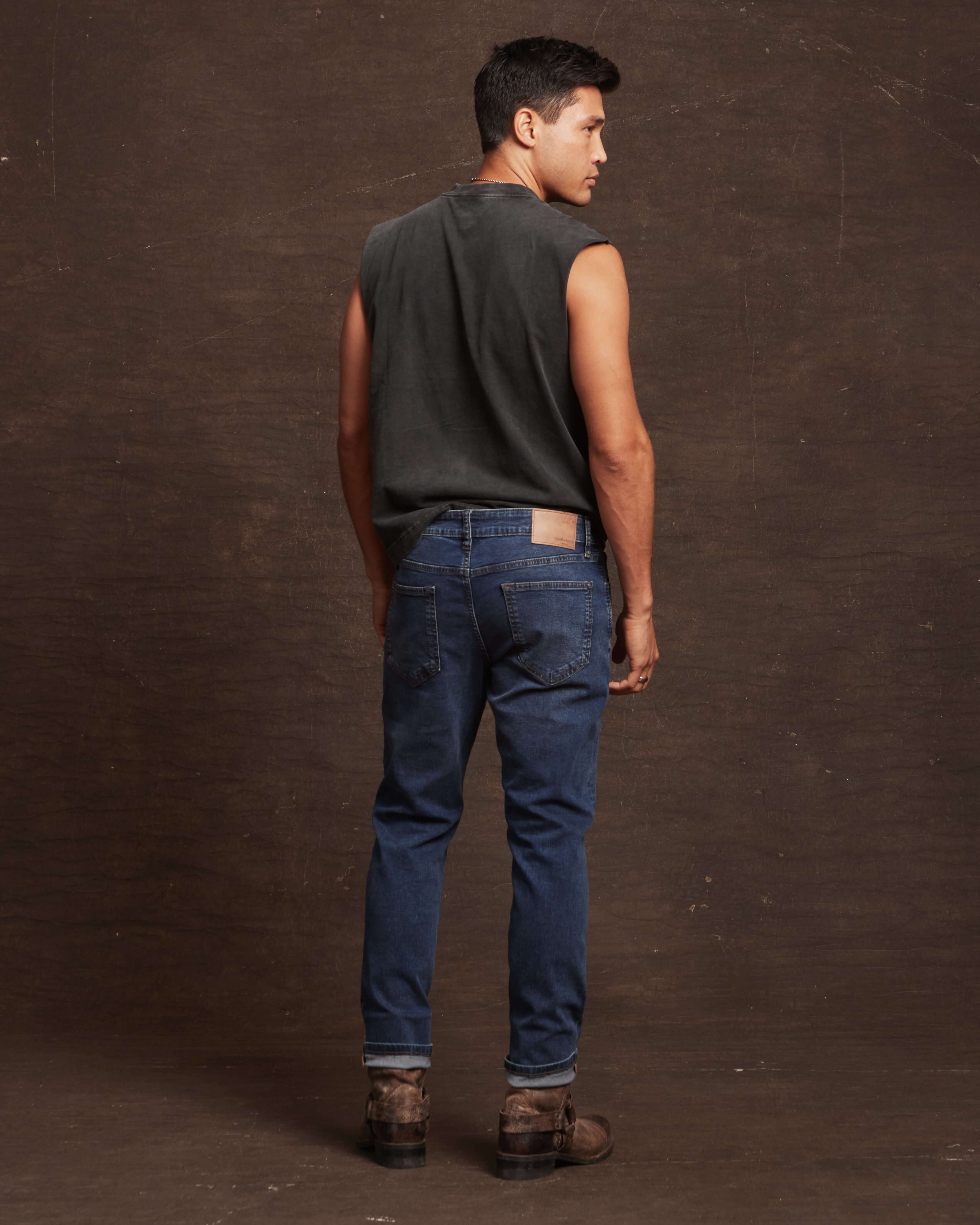 Stylish man wearing slim fit soft blue denim jeans, showcasing the back view and straight fit design.