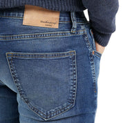 Close-up of slim fit denim jeans in soft blue, showcasing back pocket and logo detail for stylish fit and comfort.