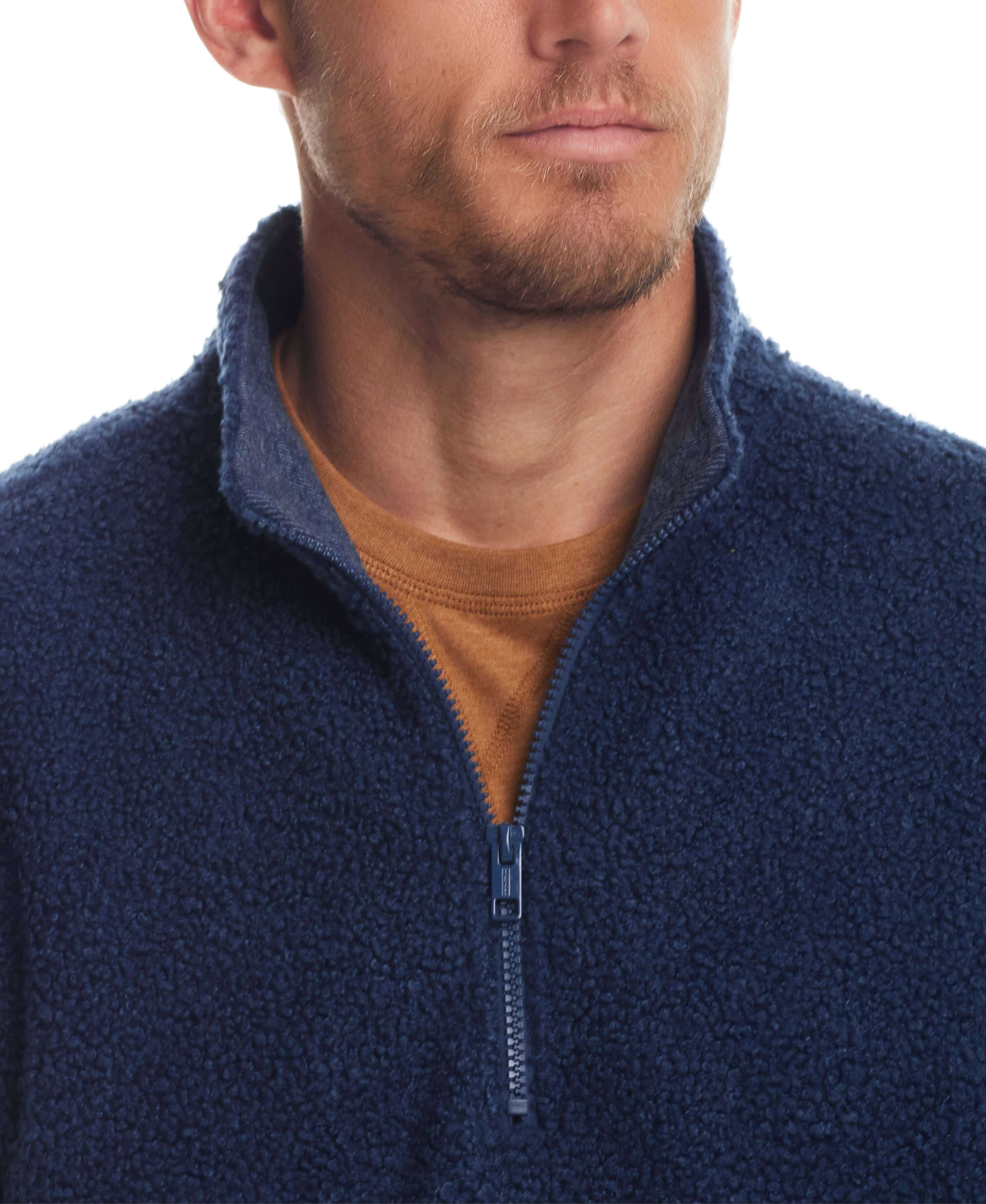 Close-up of a man in a Teddy Sherpa Pullover featuring a quarter zip in Pageant Blue, showcasing its plush fleece texture.