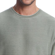 Close-up of a soft cotton twill stonewash sweater in moss, featuring a classic roll-neck design and textured rib knit.