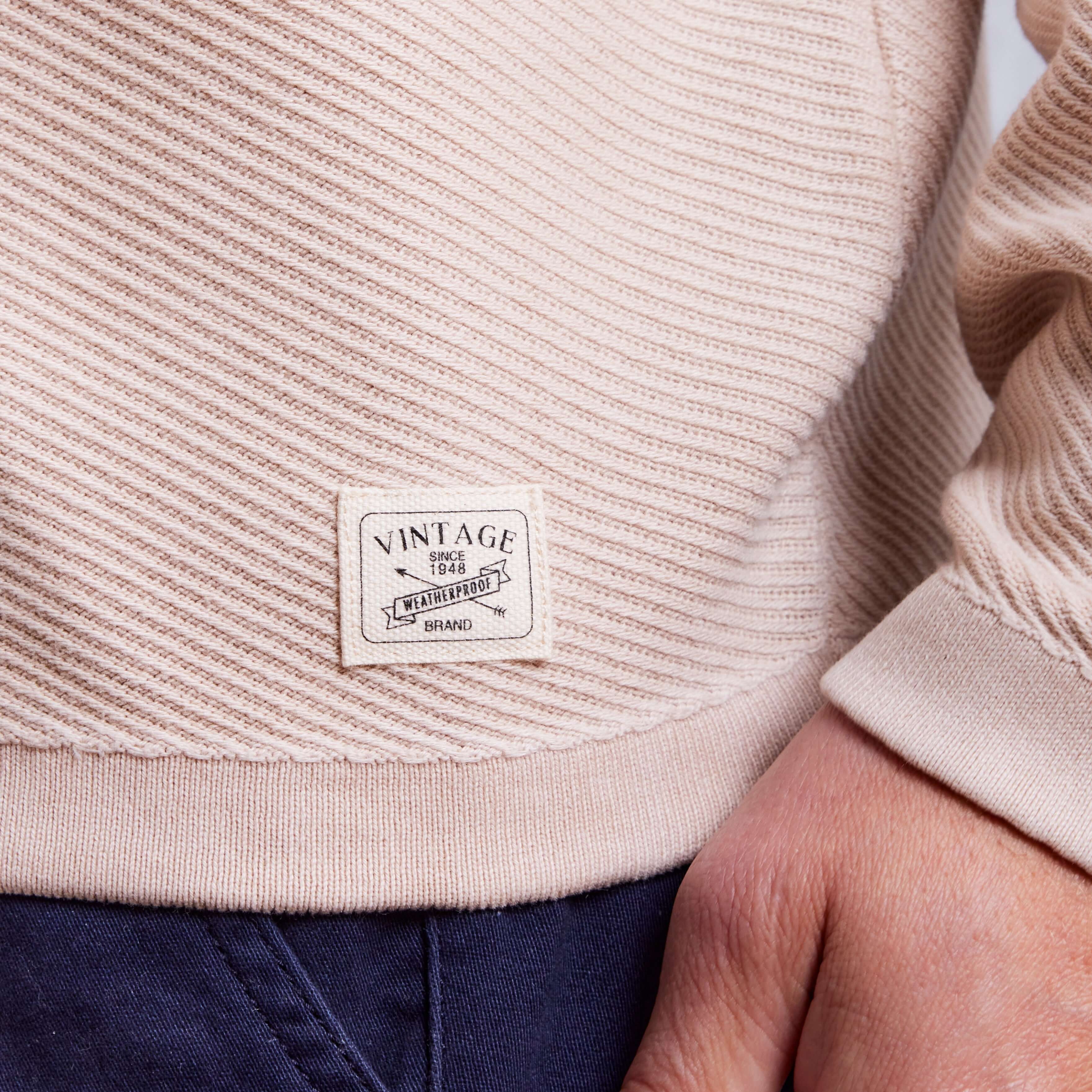 Close-up of Twill Stonewash Sweater in Natural showing vintage logo tag and texture detail.
