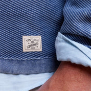 Vintage label on a blue stonewash sweater showcasing textured knit detail and a timeless fashion statement.