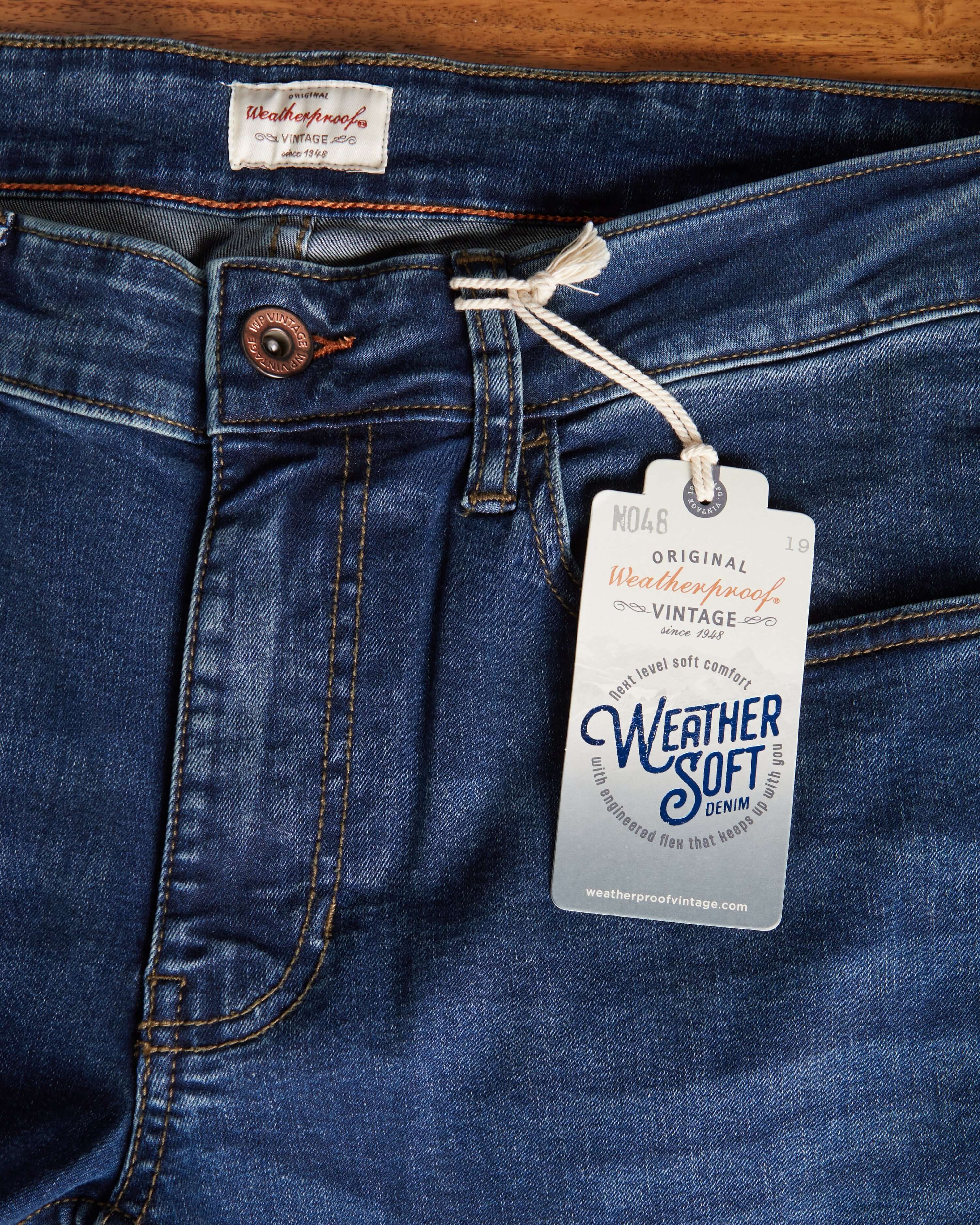 Close-up of Weatherproof Vintage slim fit denim jeans with tag showcasing Weather Soft technology in a deep blue wash.