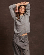 Stylish woman modeling a women's cashmere long sleeve crew sweater in medium grey, paired with relaxed fit pants.