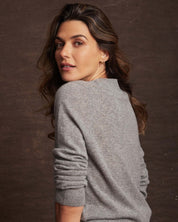 Model wearing a women's medium grey cashmere long sleeve crew sweater, showcasing its softness and classic fit.