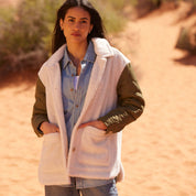 Woman wearing a cozy Women's Quilted Mixed Media Jacket in green and faux shearling, styled in a desert setting.