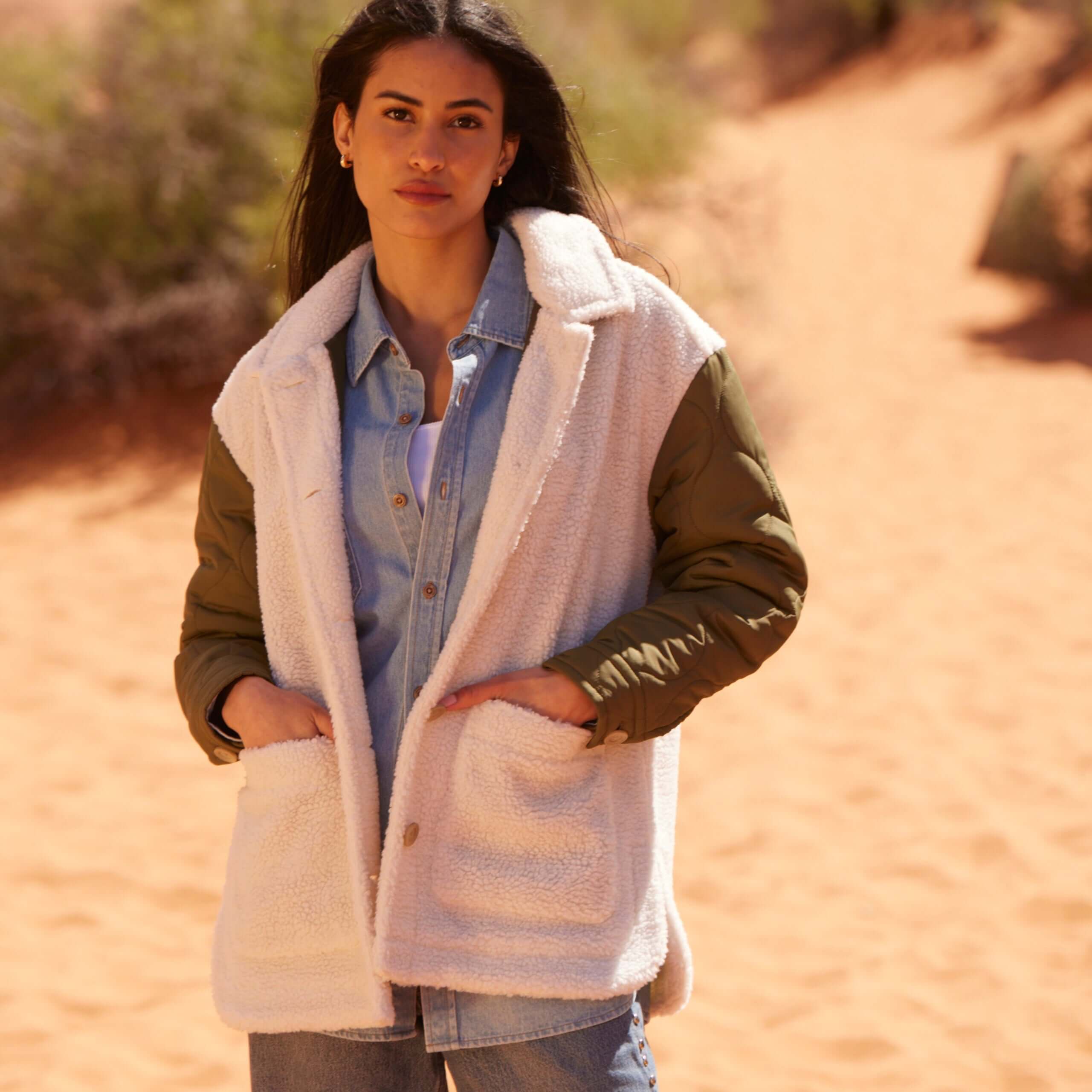 Woman wearing a cozy Women's Quilted Mixed Media Jacket in green and faux shearling, styled in a desert setting.