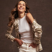 Woman smiling in casual style, wearing a lightweight plaid flannel shirt layered over a tank top.