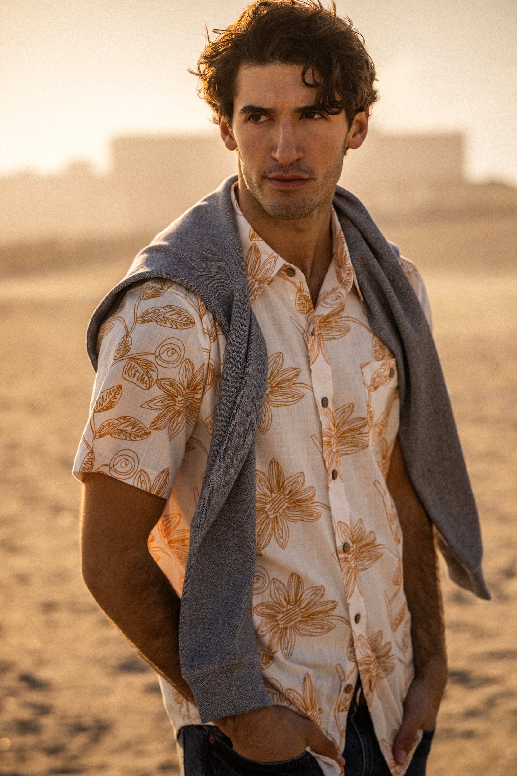 Model wearing 100% Cotton Linen-Texture Shirt in Sunrise with floral pattern and sweater on shoulders.