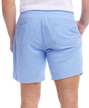 Back view of 7" linen shorts in fjord blue, featuring a comfortable elastic waistband and back patch pockets.