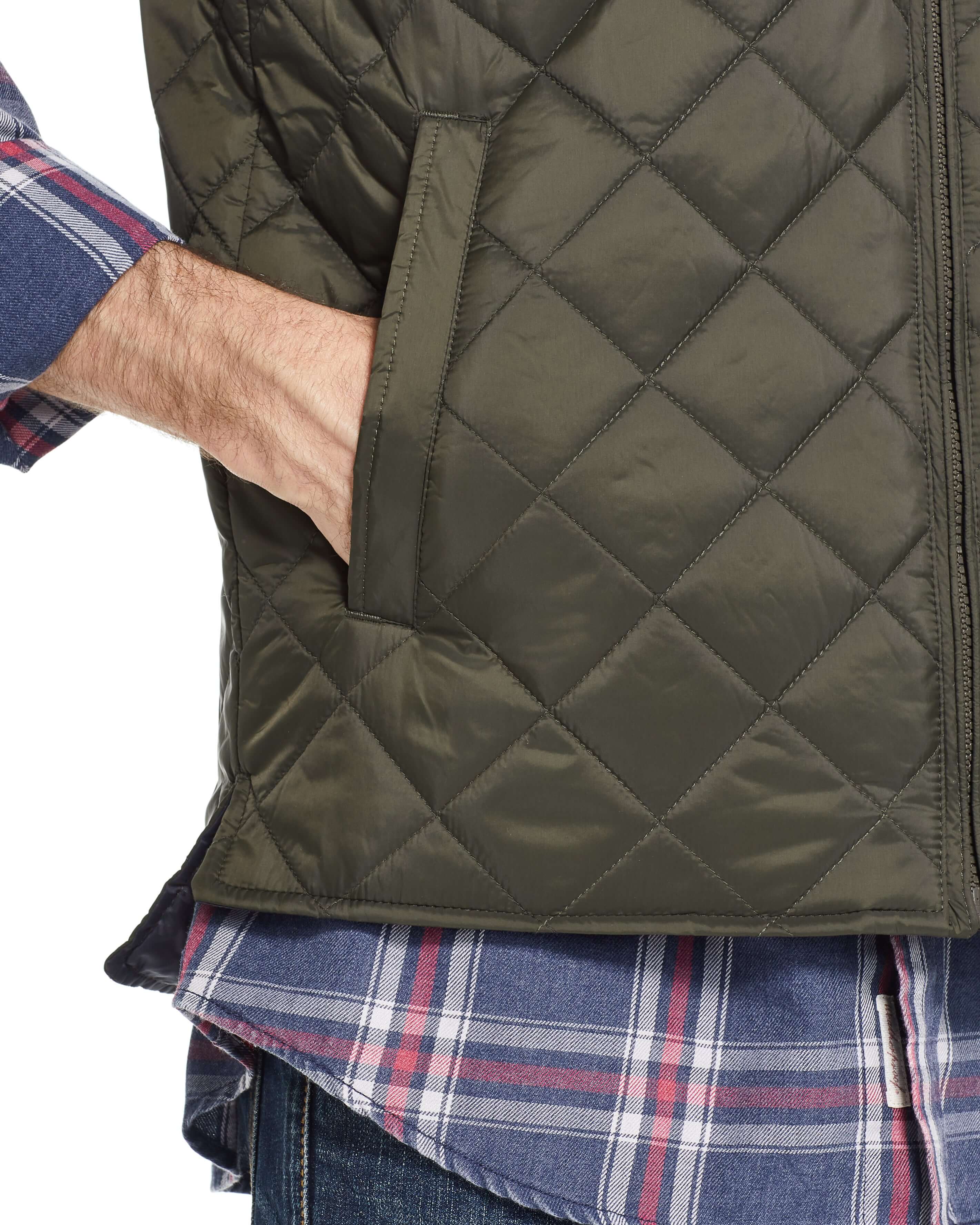Close-up of a man's hand in the pocket of a diamond quilted vest in rosin, showcasing stylish and functional design.
