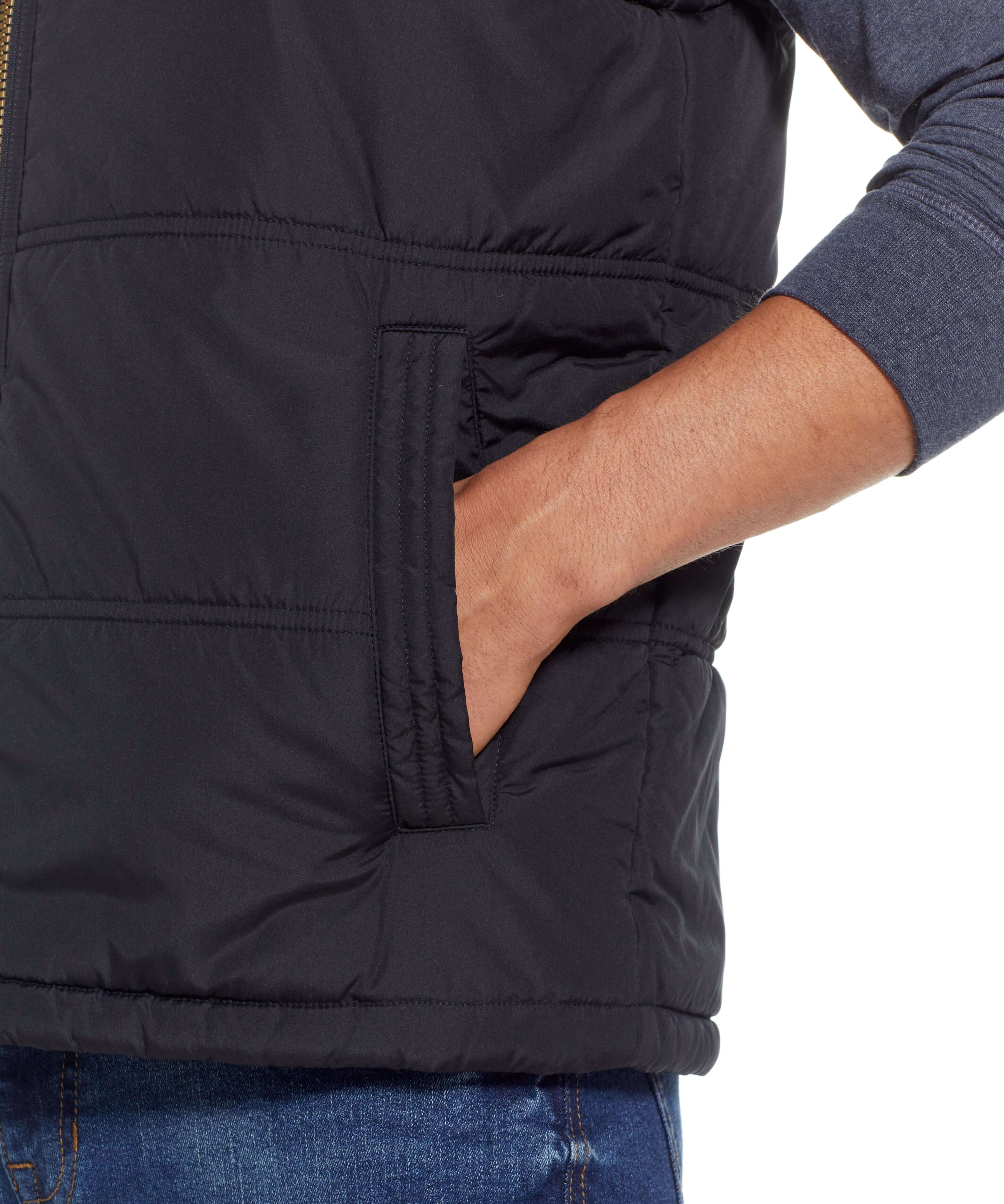 Close-up of a hand in the side pocket of a Sherpa Lined Hooded Puffer Vest In Black.