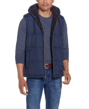 Sherpa Lined Hooded Puffer Vest In Dark Sapphire worn by a model, showcasing its cozy design and drawcord hood.