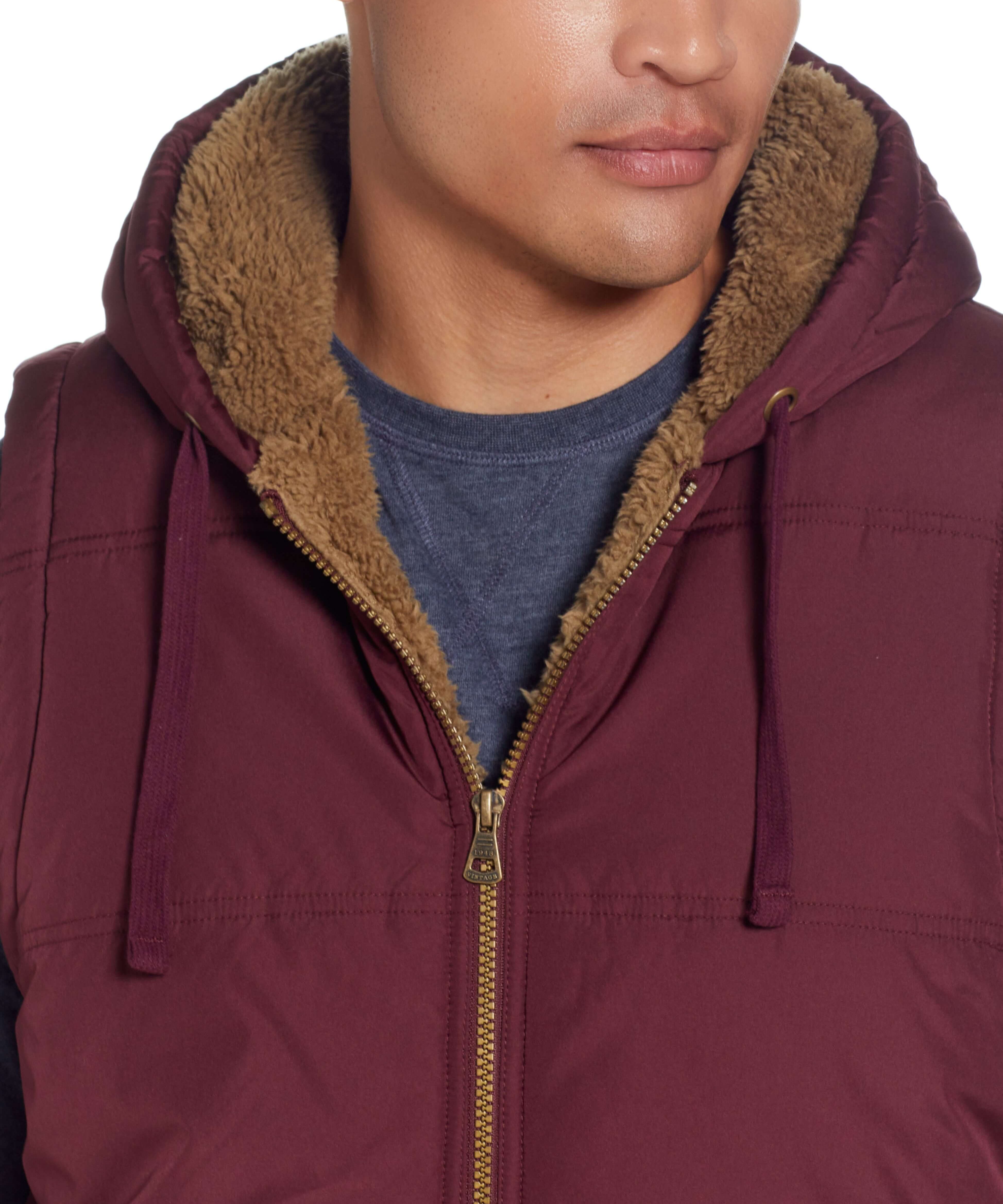 Close-up of a model wearing Sherpa Lined Hooded Puffer Vest In Port with a cozy sherpa lining and drawcord hood.