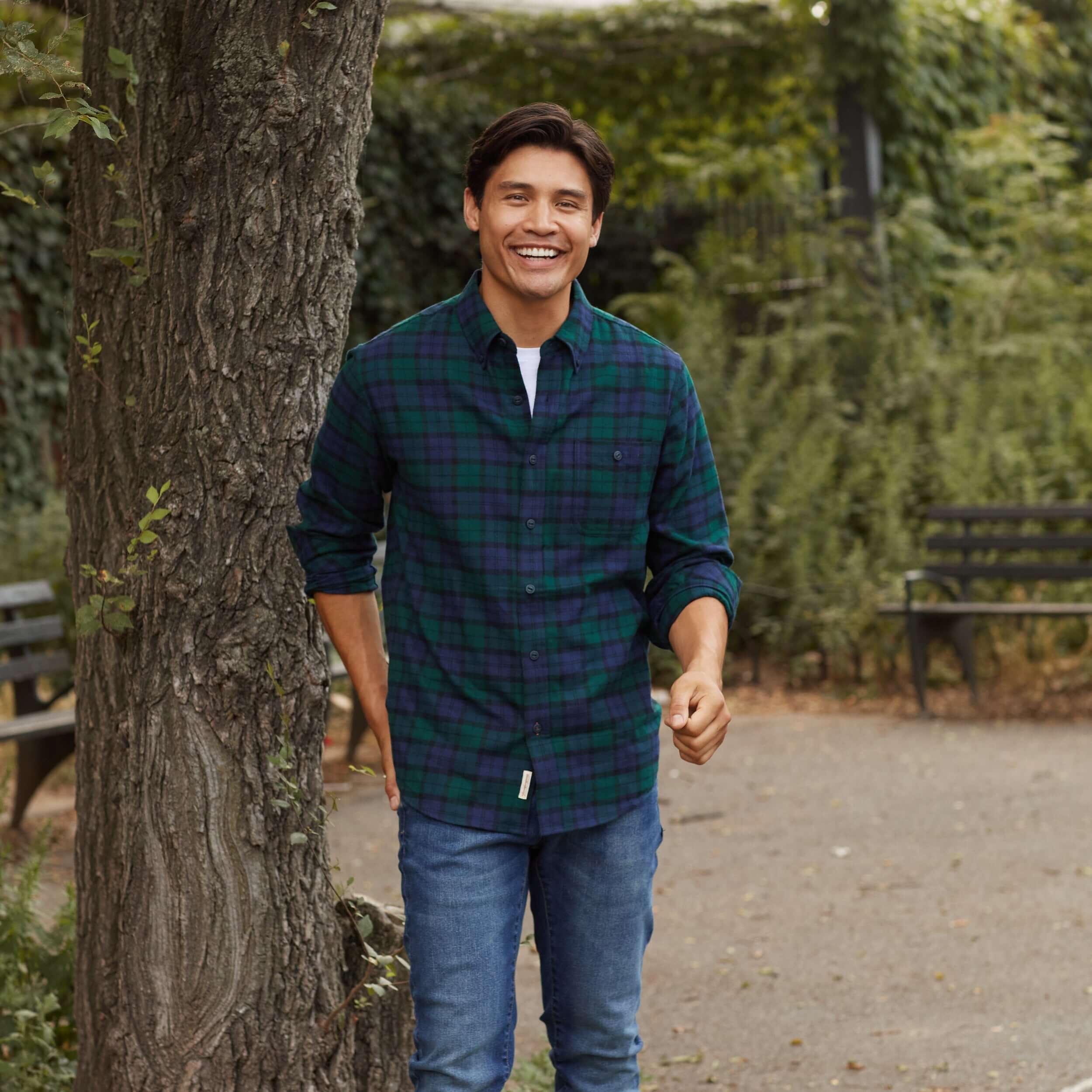 Holiday Antique Flannel Shirt In Deep Sea worn by a smiling model outdoors with trees and benches.