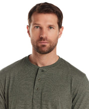 Man wearing a short sleeve microstripe henley in pine, featuring a ribbed collar and button placket.