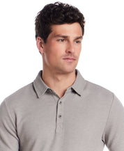 Man wearing a short sleeve stretch waffle polo in Ultimate Grey with a classic collar and three-button placket.