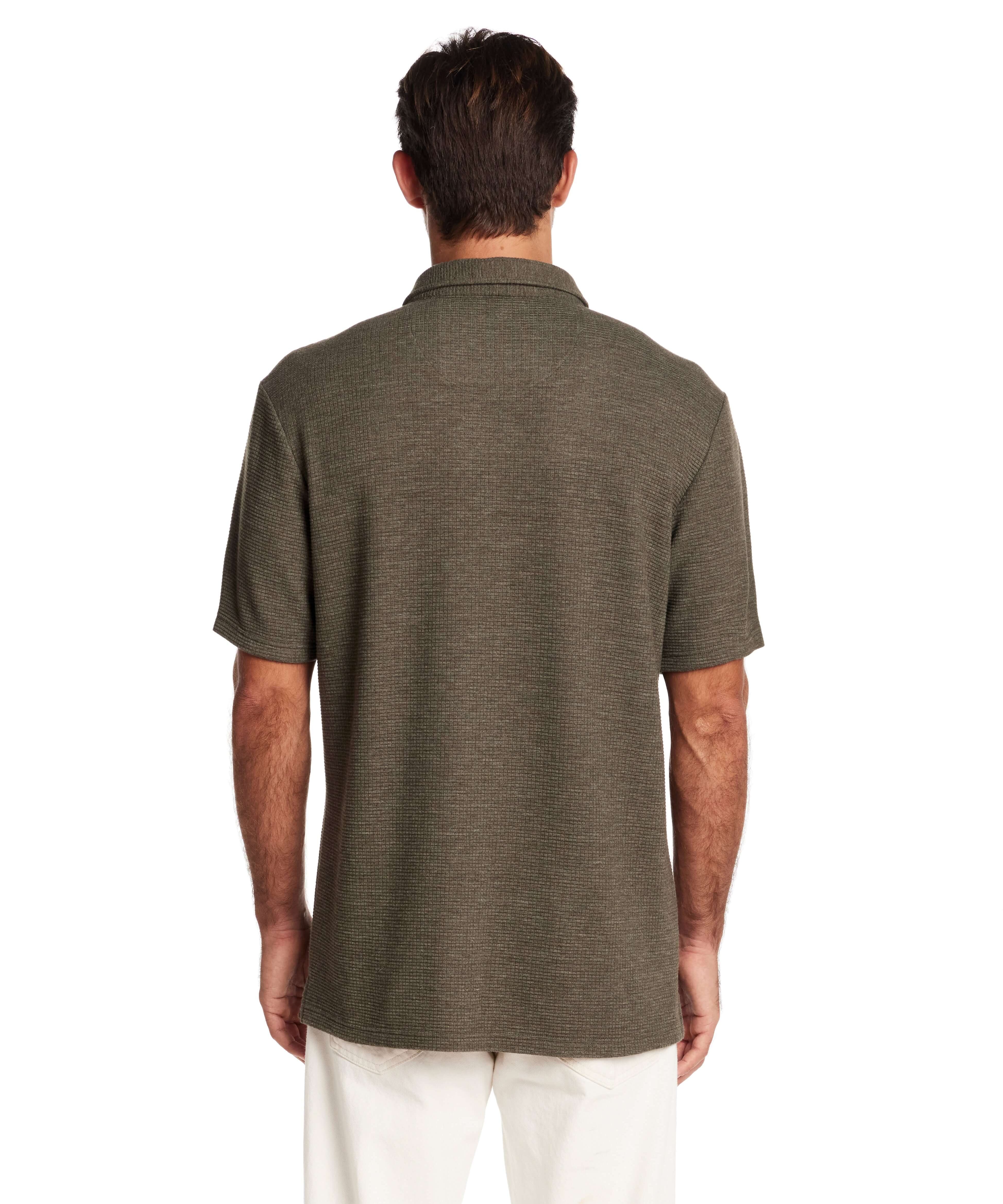 Back view of a man wearing a short sleeve olive heather waffle knit shirt, showcasing a relaxed fit and collar detail.